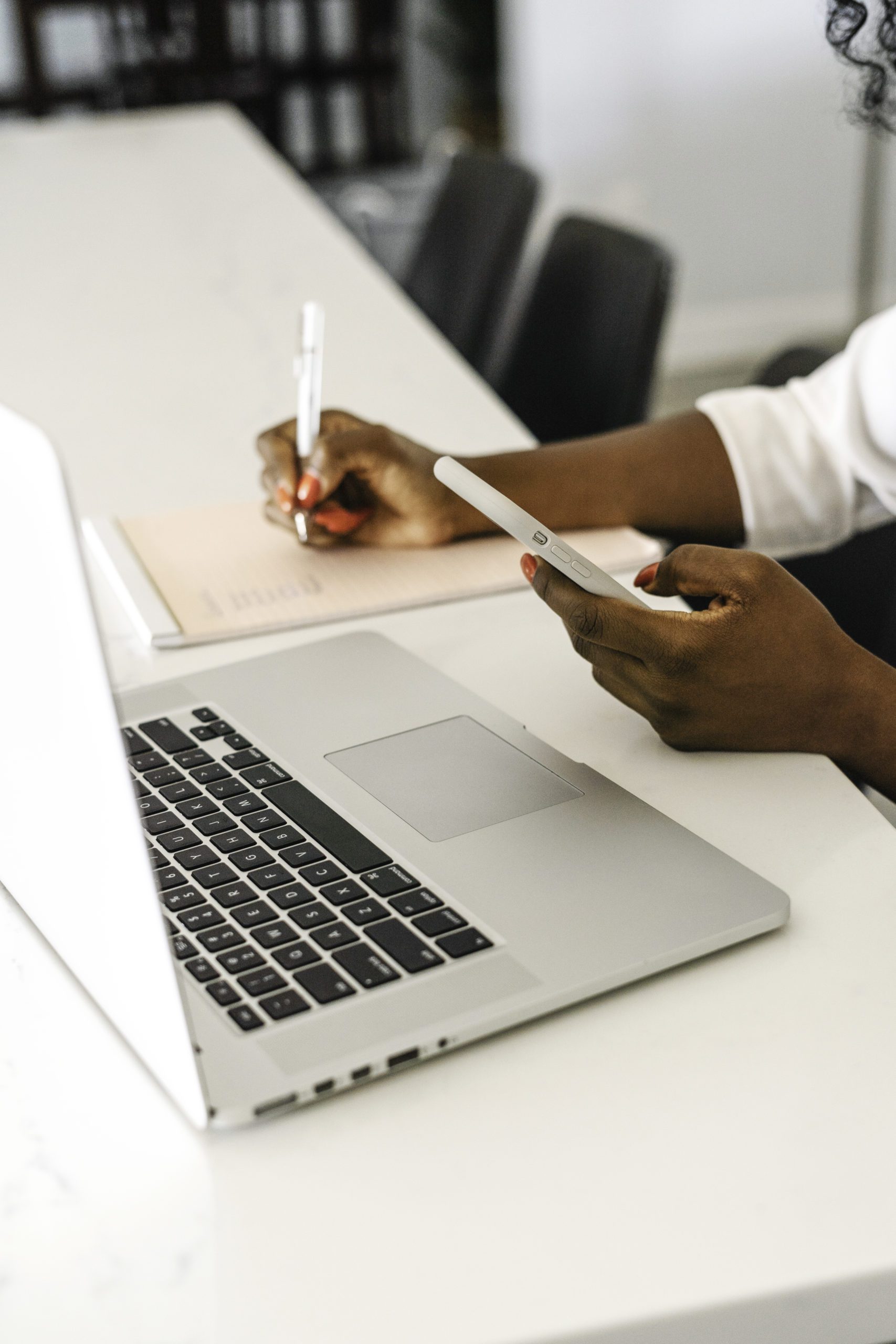 woman with phone and laptop taking notes